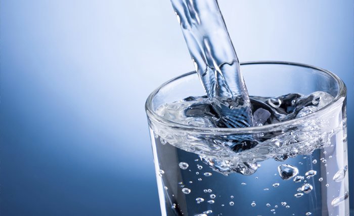 Photo of crystal clear water pouring into a water glass