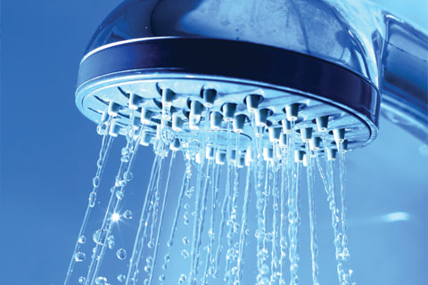 Photo of a shower head flowing freely with no more clogging due to hard water mineral buildup.